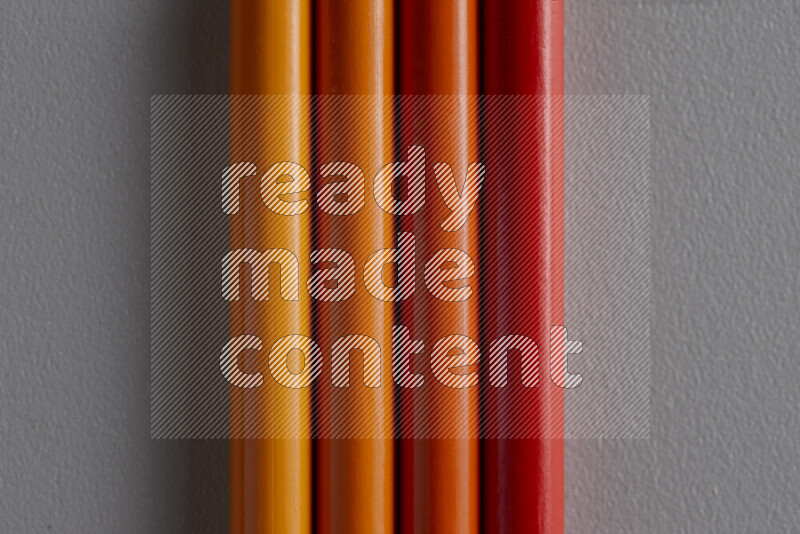 A collection of colored pencils arranged showcasing a gradient of orange hues on grey background