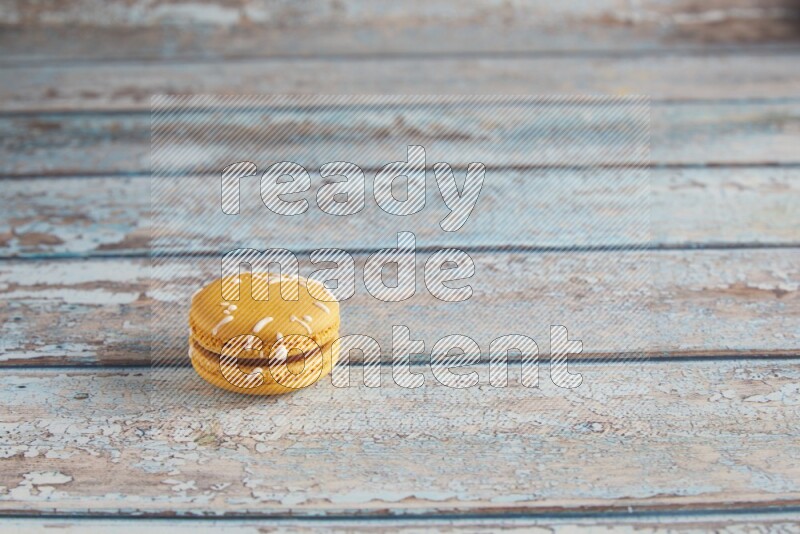 45º Shot of Yellow Piña Colada macaron on light blue wooden background