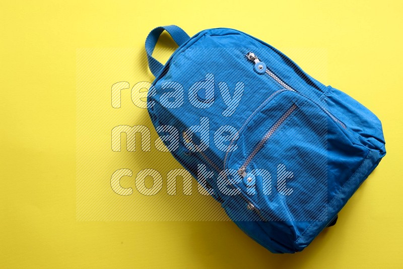 A school bag on yellow background (back to school)