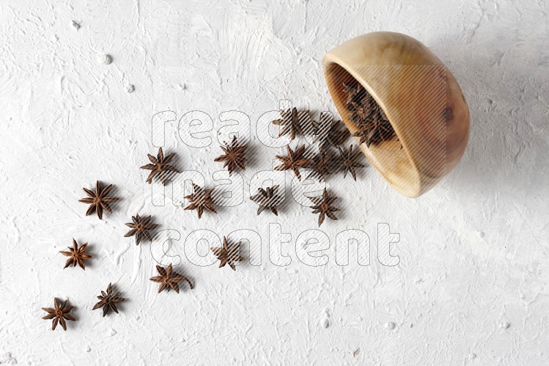 Star anise lined out of wooden plate across the frame on white background