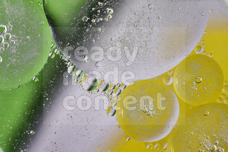 لقطات مقربة لفقاعات من الزيت على سطح الماء باللون الأصفر والأخضر والأبيض