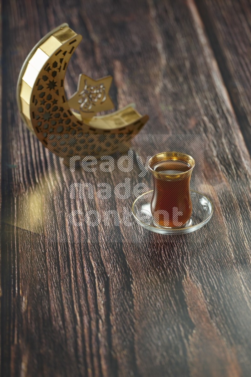 A wooden golden crescent lantern with different drinks, dates, nuts, prayer beads and quran on brown wooden background
