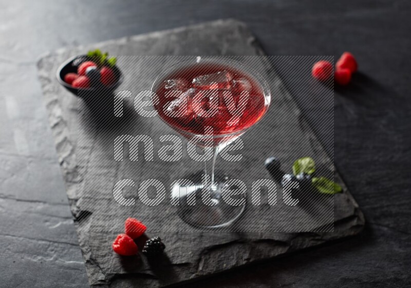 A glass of mixed berries juice on black background
