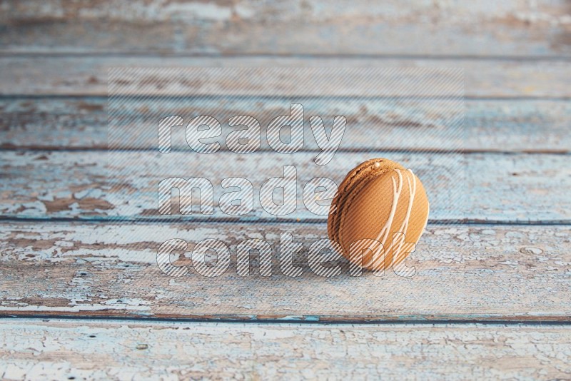 45º Shot of Brown Irish Cream macaron on light blue wooden background