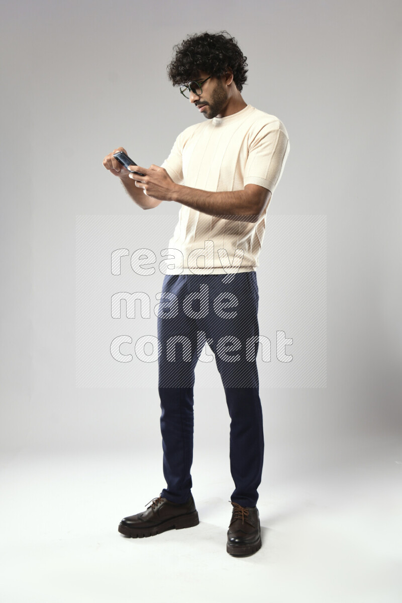 A man wearing casual standing and browsing on the phone on white background