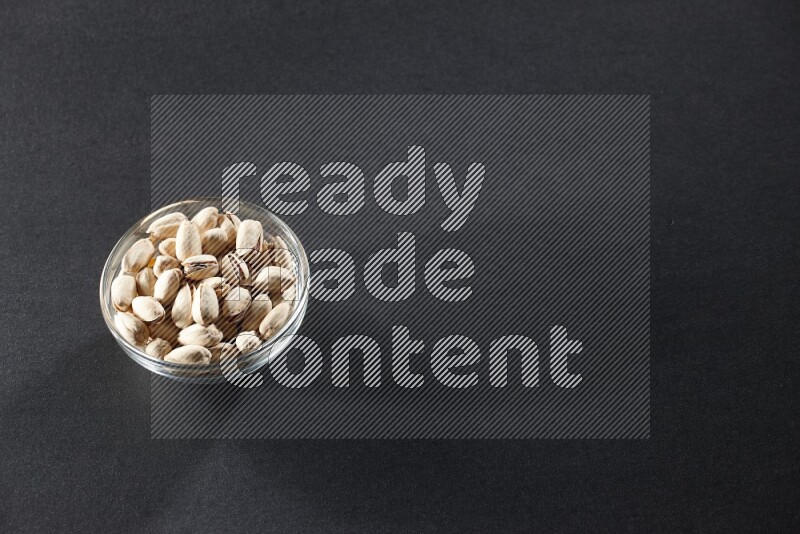 وعاء زجاجي ممتلئ بالفستق على خلفية سوداء