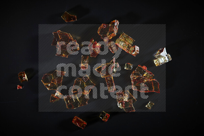 Transparent orange fragments of glass scattered on a black background