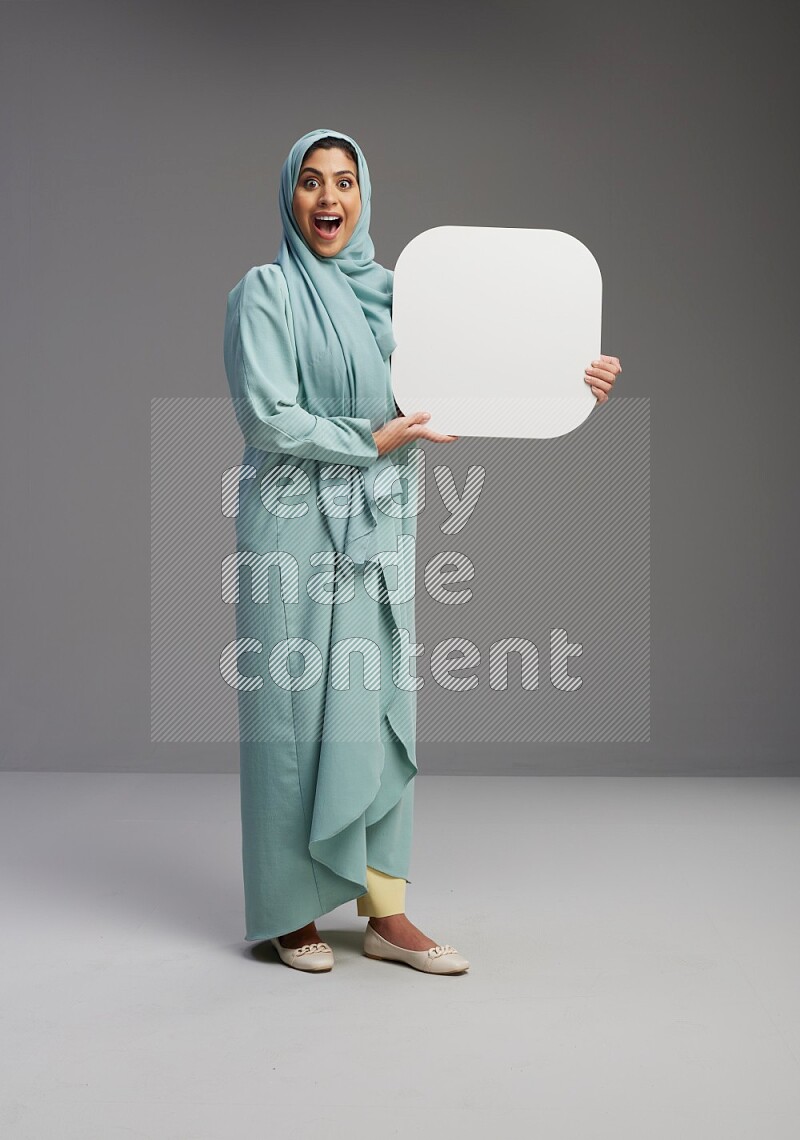 Saudi Woman wearing Abaya standing holding social media sign on Gray background