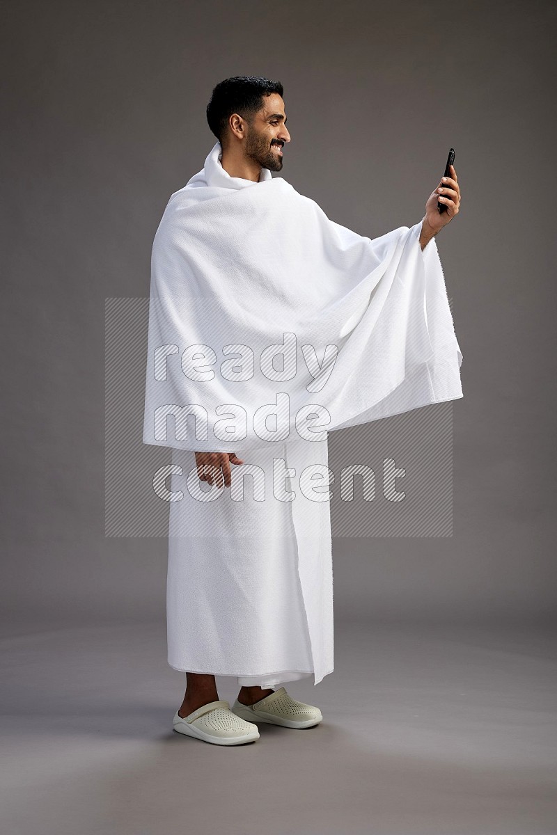 A man wearing Ehram Standing taking selfie on gray background