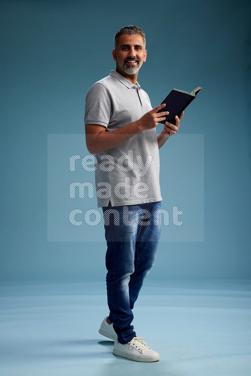 Man Standing reading book on blue background