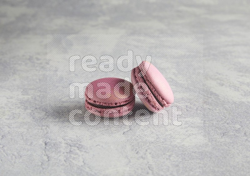 45º Shot of two Purple Strawberry macarons on white  marble background