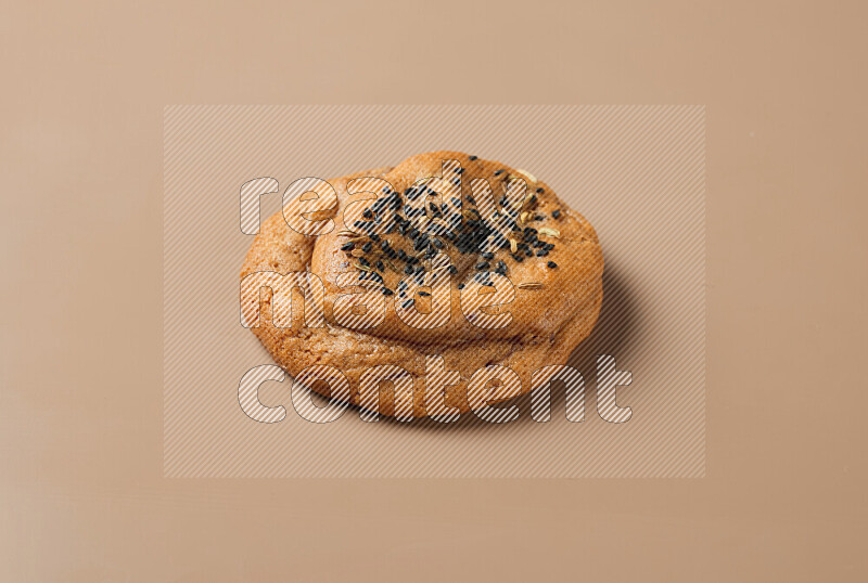 a whole Hasawi cookie with grains on a brown background