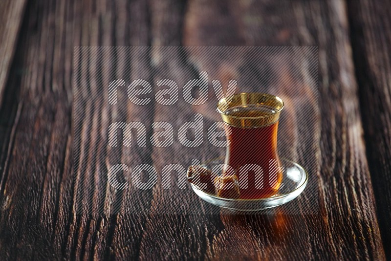 كوب زجاجي من الشاي مع التمر والقهوة على خلفية خشبية