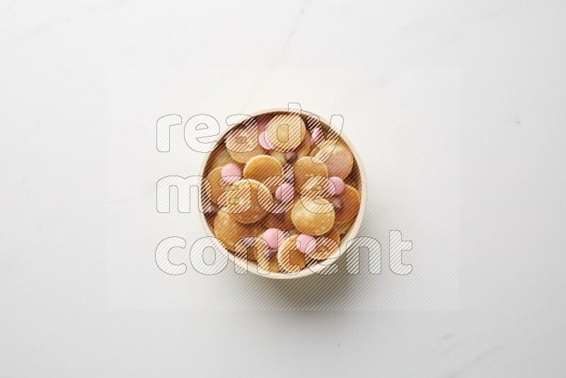 Top-view shot of mixed chocolate chips cereal pancakes in a round bowl on white background