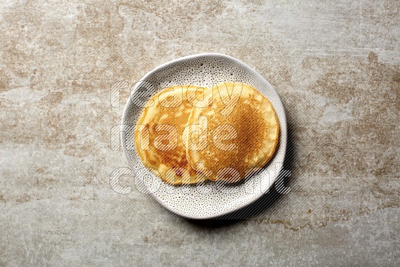 Two stacked plain pancakes in an irregular plate on beige background