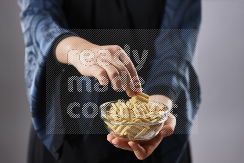 Woman in abaya holding different kinds of snacks in different positions