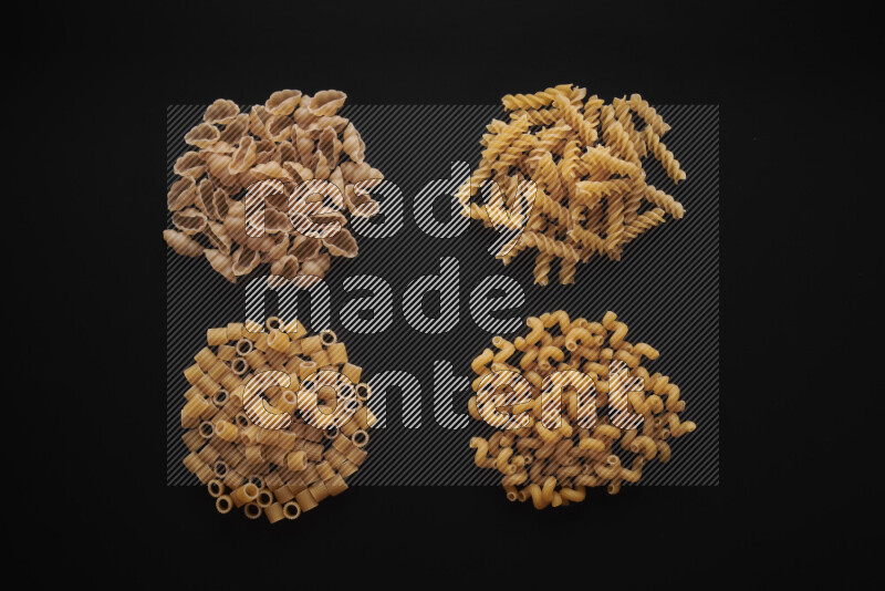 Different pasta types in bunches on black background