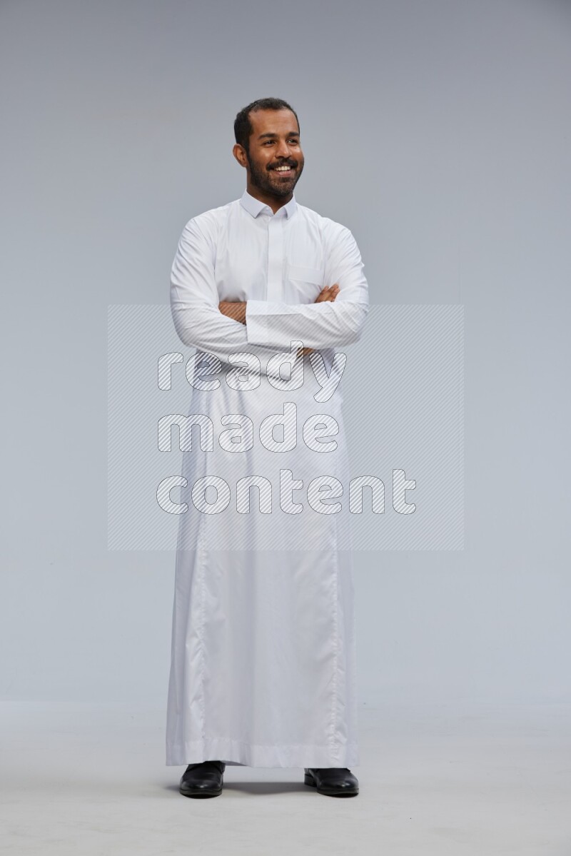 Saudi man wearing Thob standing with crossed arms on Gray background