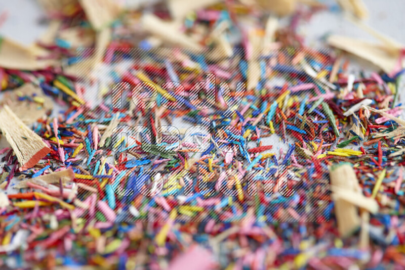 This image showcases a vibrant multicolored pencil shavings scattered on grey background