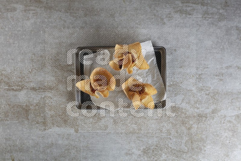 wonton cups on parchment paper in stainless tray on grey textured counter top