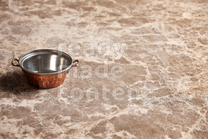 A small copper pot on beige marble background