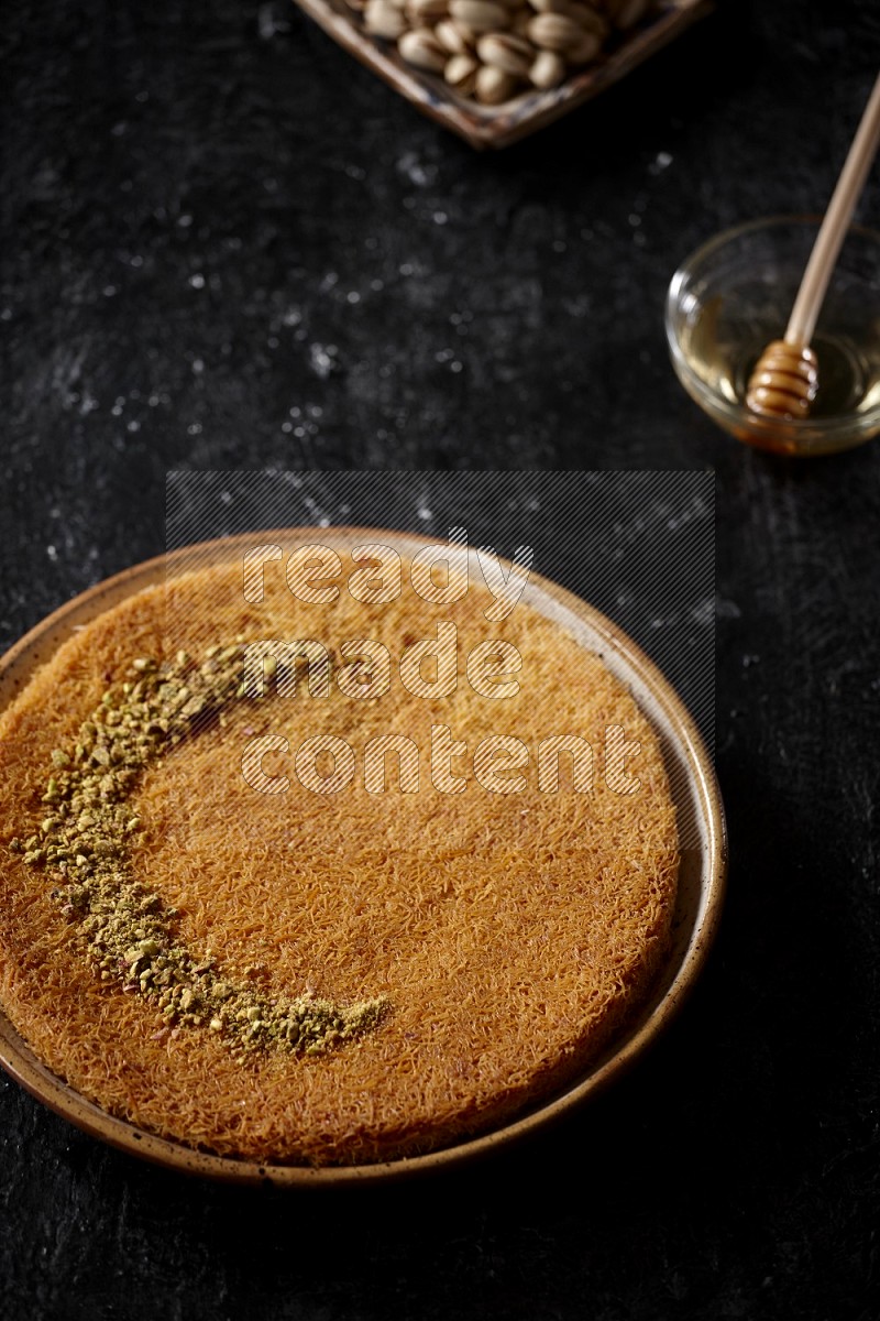 Konafa with nuts and honey in a dark setup