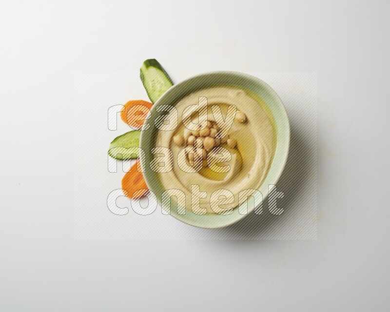 Hummus in a green plate garnished with roasted chickpeas  on a white background