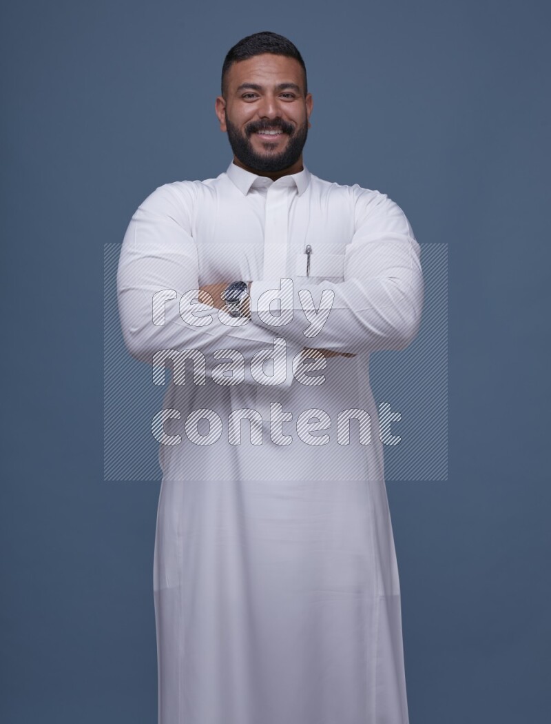 A man Posing in Blue Background wearing a Saudi Thob