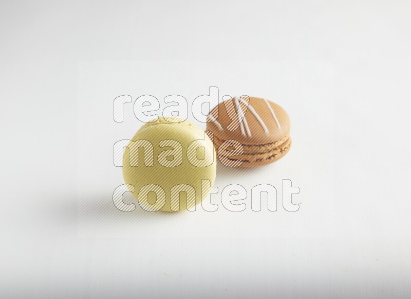 45º Shot of of two assorted Brown Irish Cream, and Yellow Lime macarons on white background