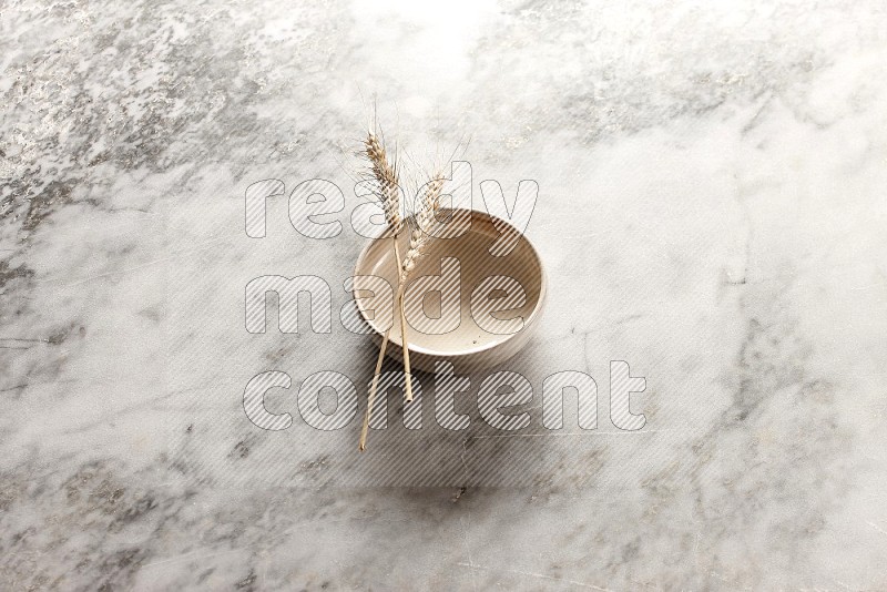 Wheat stalks on Beige Pottery Bowl on grey marble flooring, 45 degree angel