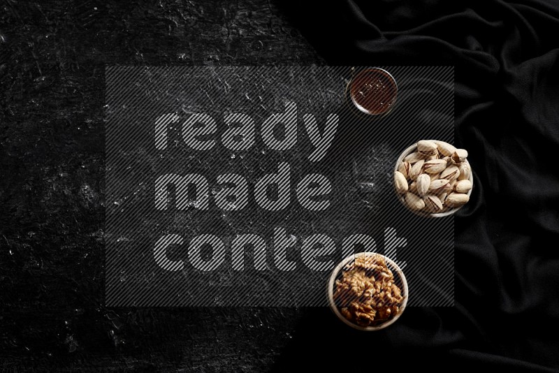 Nuts in pottery bowls with coffee in a dark setup