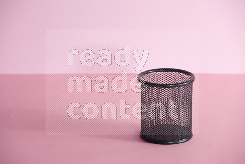 Pens, pencils and other different school supplies in a metal pen holder on rose background