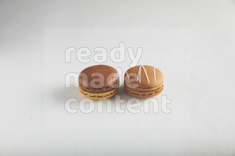 45º Shot of of two assorted Brown Irish Cream, and Yellow, and Brown Chai Latte macarons on white background