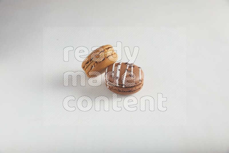 45º Shot of of two assorted Brown Irish Cream, and Brown white Chocolate Caramel macarons on white background