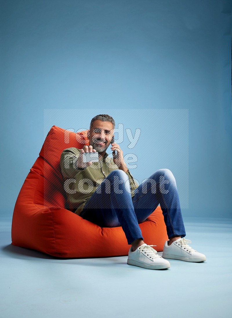 A man sitting on an orange beanbag and holding ATM card