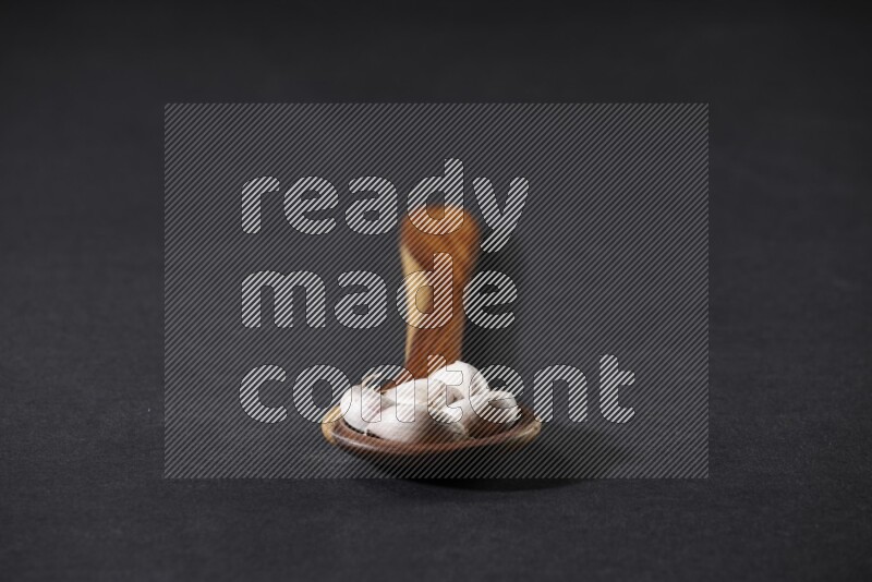 ملعقة خشبية كبيرة مليئة بفصوص الثوم على خلفية سوداء