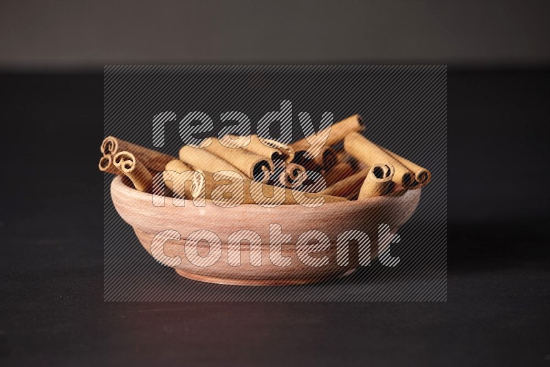 Cinnamon Sticks in a wooden bowl on black background