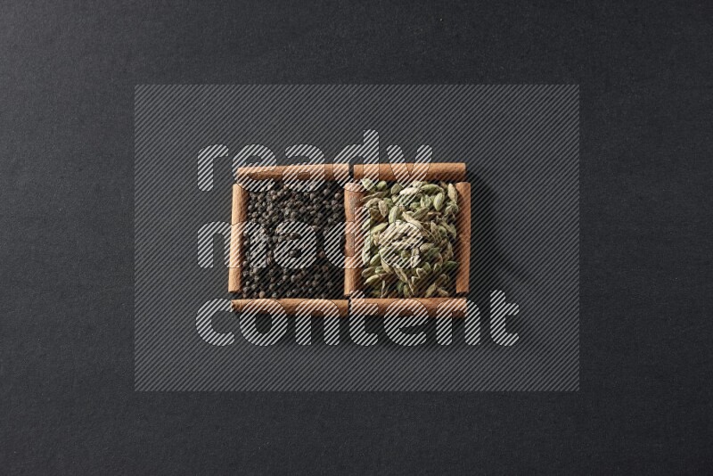 2 squares of cinnamon sticks full of black peppers and cardamom on black flooring
