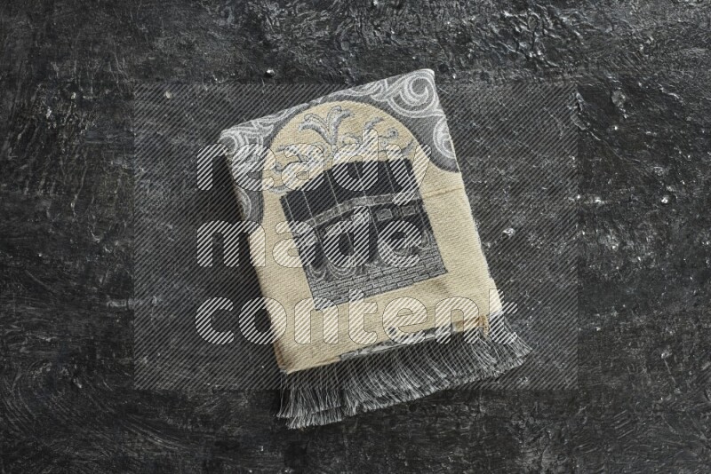 سجادة صلاة مطوية بعناصر مختلفة مثل القرآن الكريم وسبحة الصلاة على خلفية سوداء