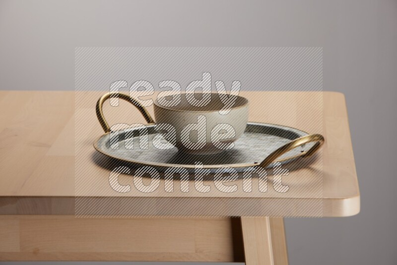 multicolored bowl placed on a rounded stainless steel tray with golden handels on the edge of wooden table