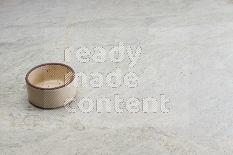A beige pottery oven bowl on grey marble background