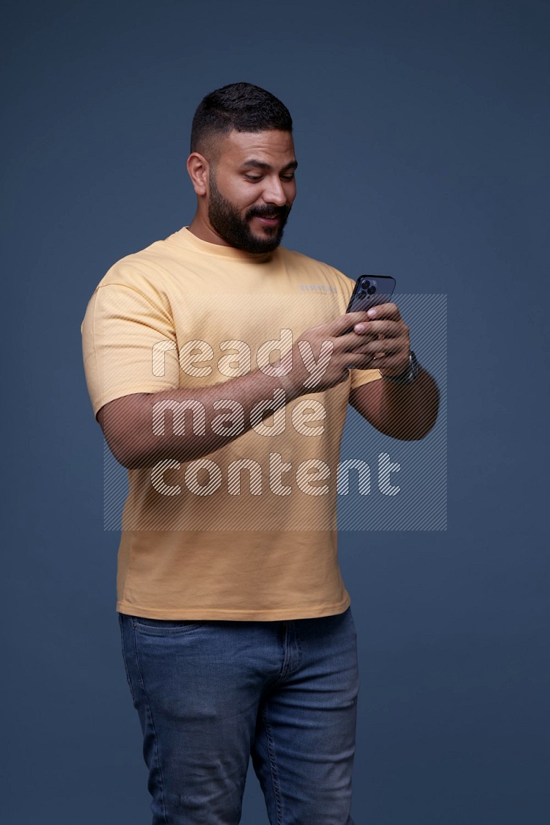 A man Texting on his phone in Blue Background wearing Orange T-shirt