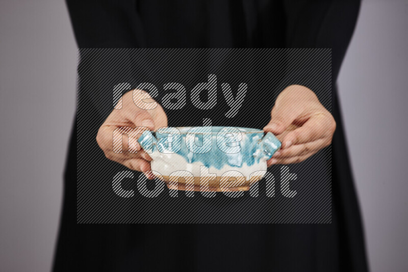 A woman in black abaya holding different pottery essentials in different positions