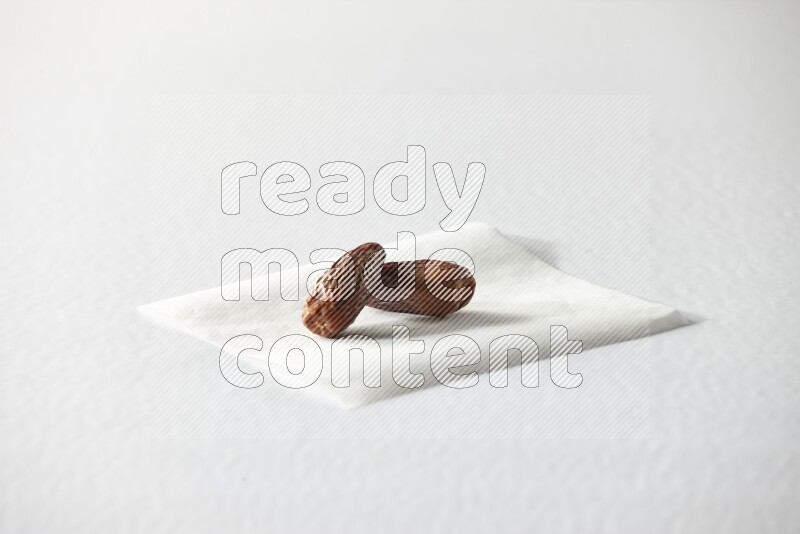 Two dried dates on a piece of paper on a white background in different angles