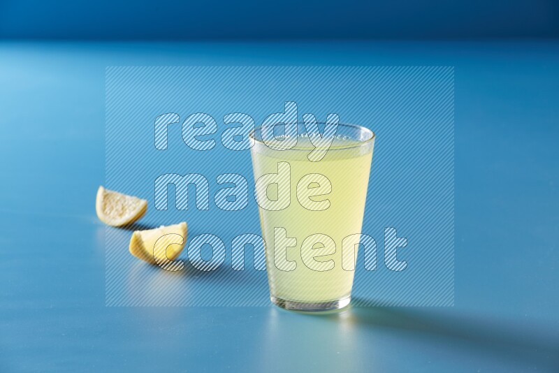 glass of lemon juice on blue background