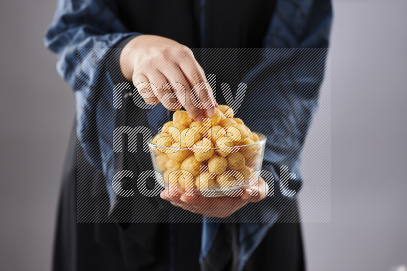 Woman in abaya holding different kinds of snacks in different positions
