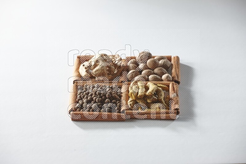 4 squares of cinnamon sticks full of nutmegs, dried ginger, turmeric fingers and allspice on white flooring