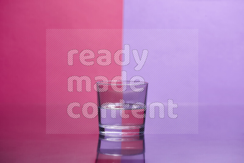 The image features a clear glassware filled with water, set against pink and light purple background