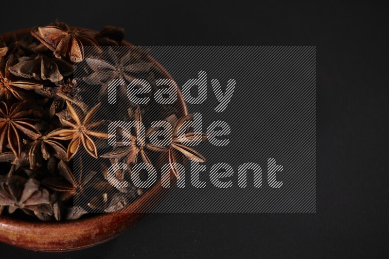 Star Anise in a wooden bowl on black flooring