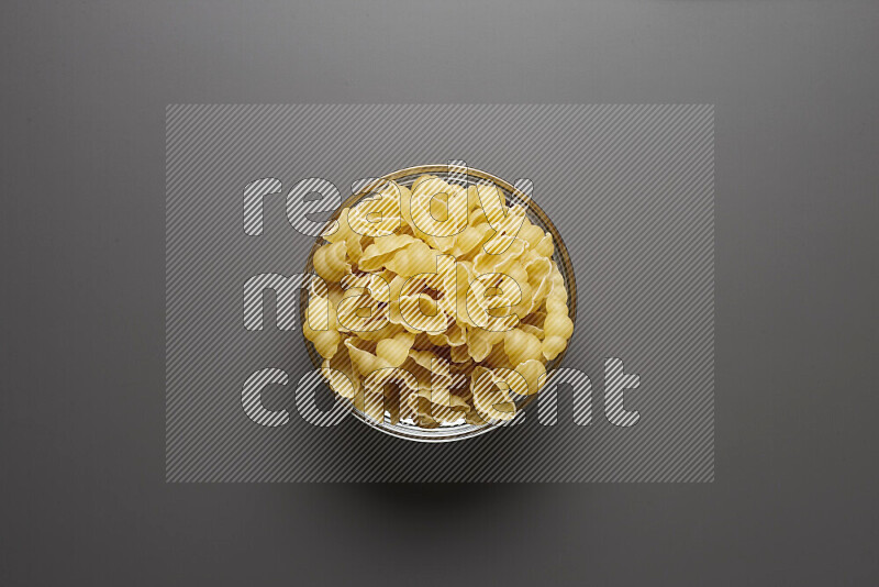 Snails pasta in a glass bowl on grey background